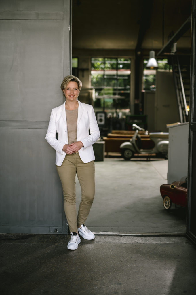 Frau im weißen Blazer vor einer Wand