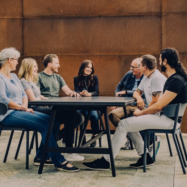 Mehrere Menschen sitzen gemeinsam am Tisch und unterhalten sich